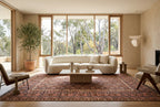 Earthy terracotta Afghan Kilim rug styled in a luxury modern organic living room with an ivory sofa, travertine coffee table and natural oak flooring.