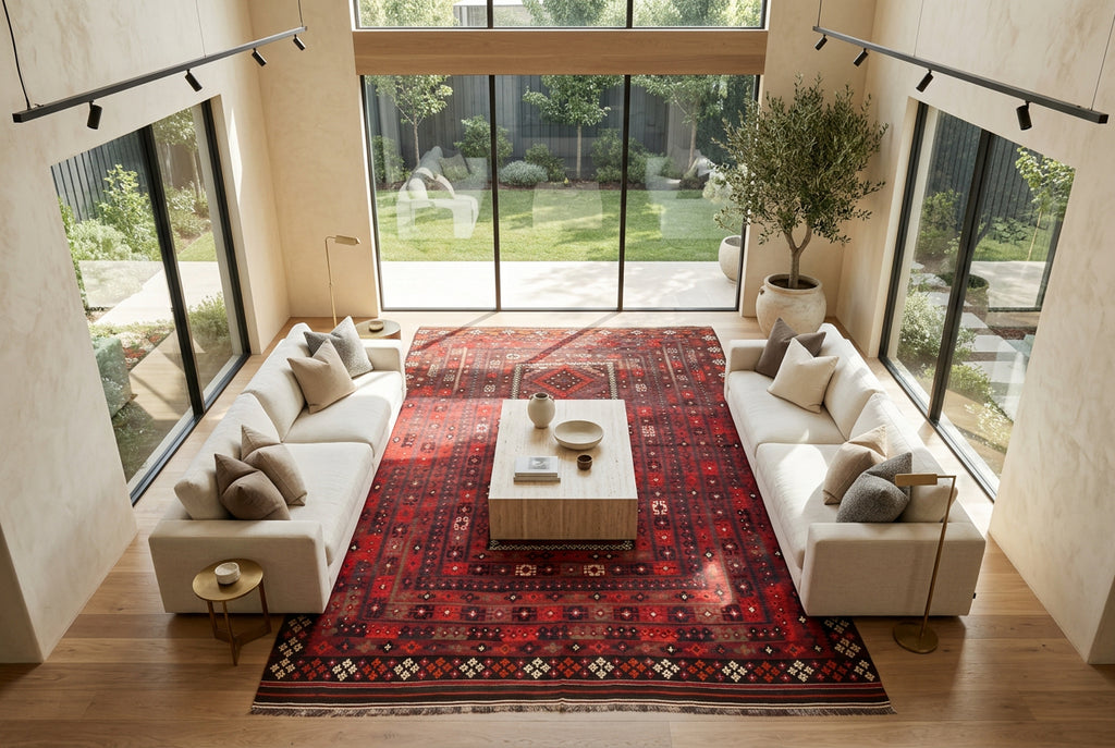 Oversized red and black Afghan Kilim rug styled in a luxury open-plan living room with cream sofas, travertine coffee table and natural oak flooring.