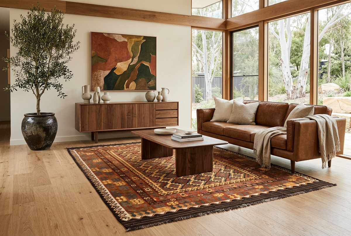 Rust orange and brown Afghan Kilim rug styled in a luxury mid-century modern living room with cognac leather sofa and walnut furniture.